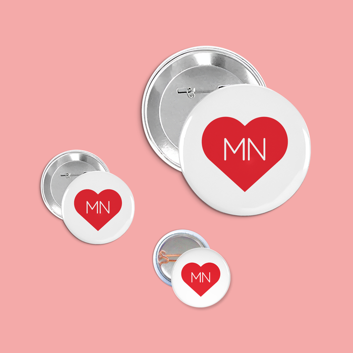 A set of buttons with red hearts and 'MN' text on a pink background