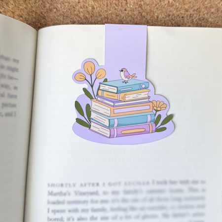 A bird standing on books magnetic bookmark in an open book.